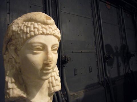 A white bust of a man with curly hair against a dark background