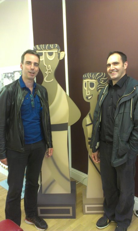 Figure 1: Ray Laurence and Andrew Park pose next to cut-outs of animated characters drawn for their TedEx series.