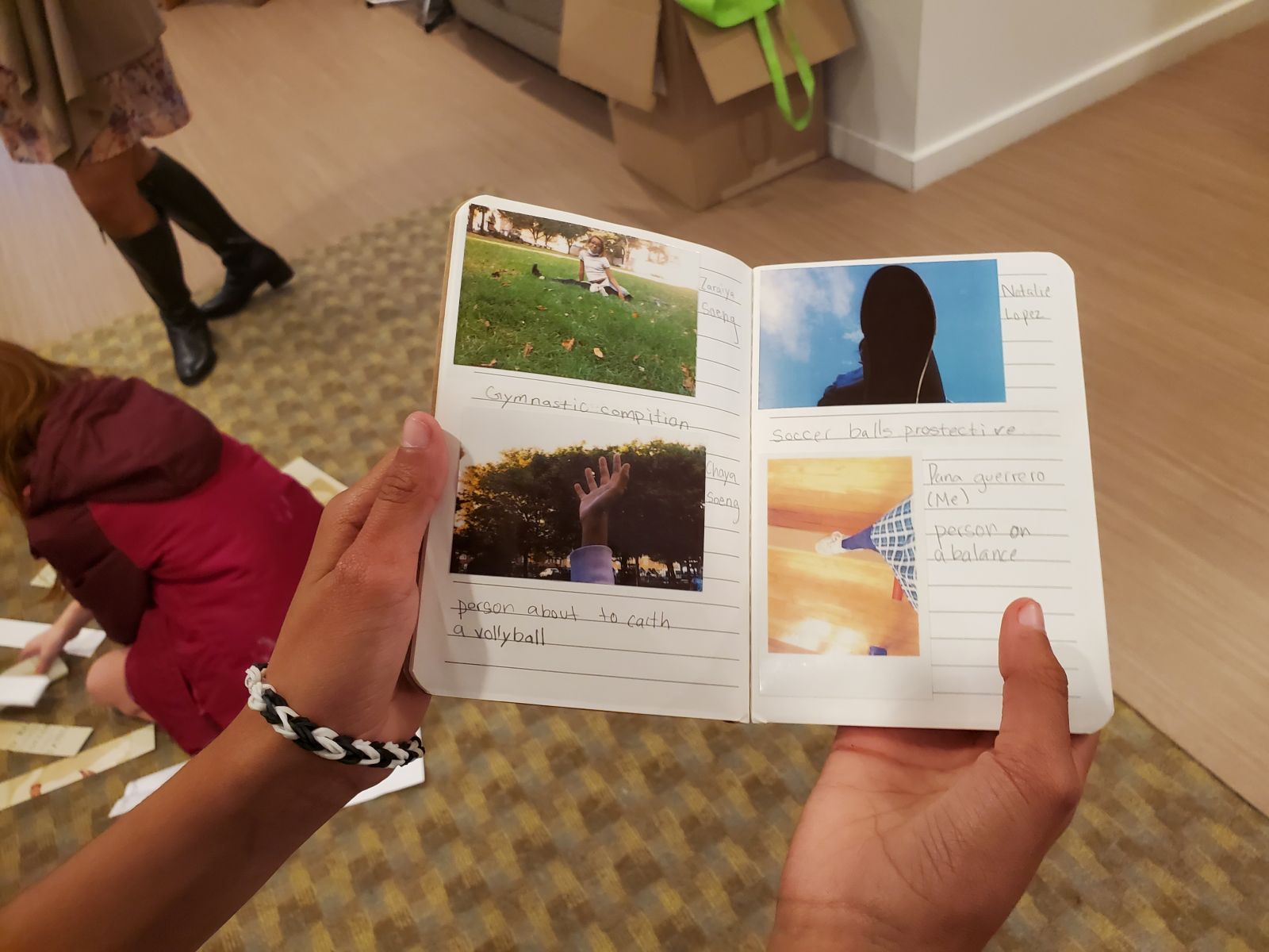 A pair of hands holding an open journal. On the journal pages are assorted photographs. Clockwise from top left: a girl sitting in the grass, a hooded figure against the sky, a person's legs, a raised hand.