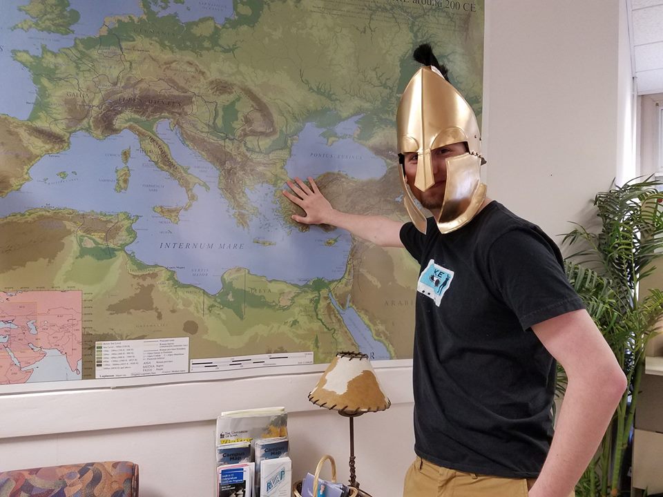 Eta Sigma Phi president, Myles Young, poses in a helmet for a promotional Facebook photo.