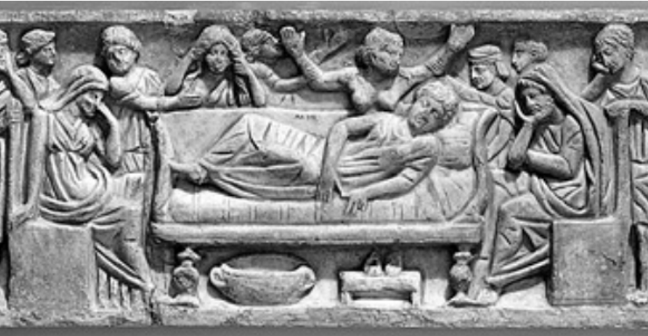 A stone relief in which a body lies on a couch, surrounded by people in different gestures of mourning.
